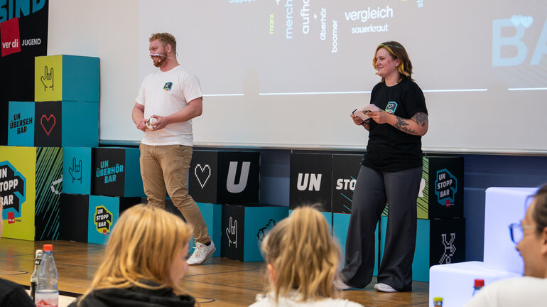 Joshua und Astrid stehen auf einer Bühne und stellen die neue Tarifkampagne Unstoppbar vor.