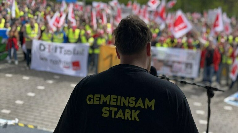 Ein Redner spricht vor einer Vielzahl Demonstrierender am bundesweiten Jugendaktionstag in der Tarifrunde Telekom 2024