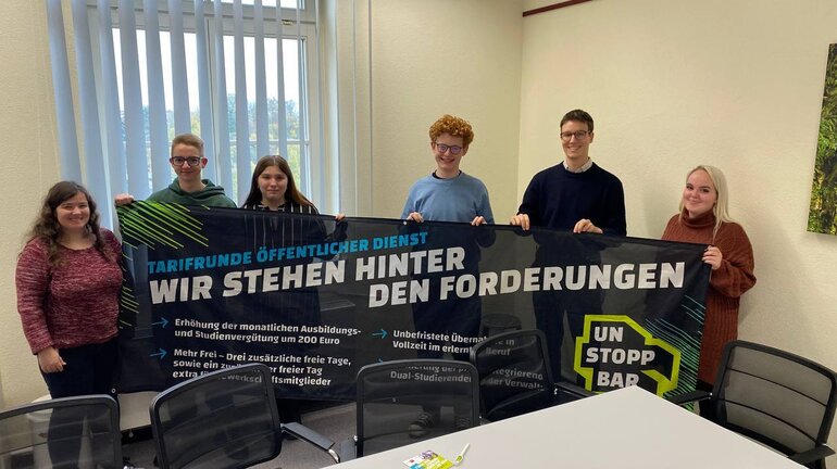 eine Gruppe an Jugendlichen hält ein Banner, auf dem die Forderungen für die Tarifrunde öffentlicher Dienst stehen.