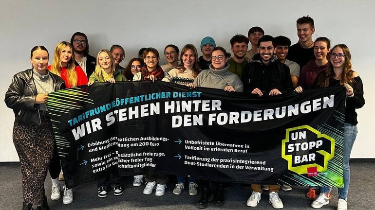 eine Gruppe an Jugendlichen hält ein Banner, auf dem die Forderungen für die Tarifrunde öffentlicher Dienst stehen.