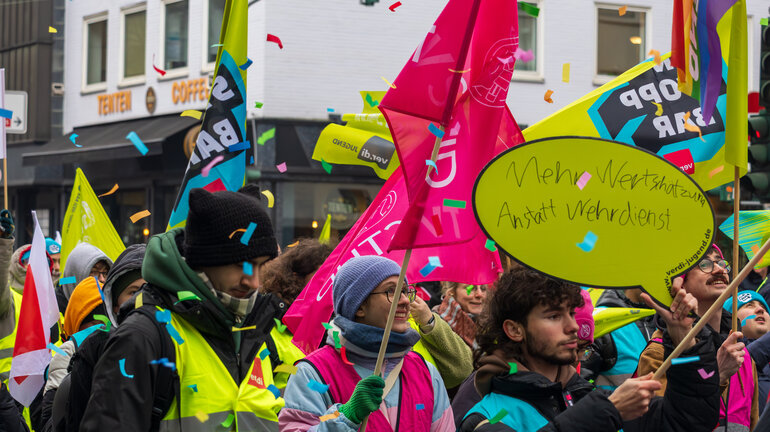 Jugendliche laufen bei einem Streik durch die Straßen und tragen Fahnen, Banner und Schilder.