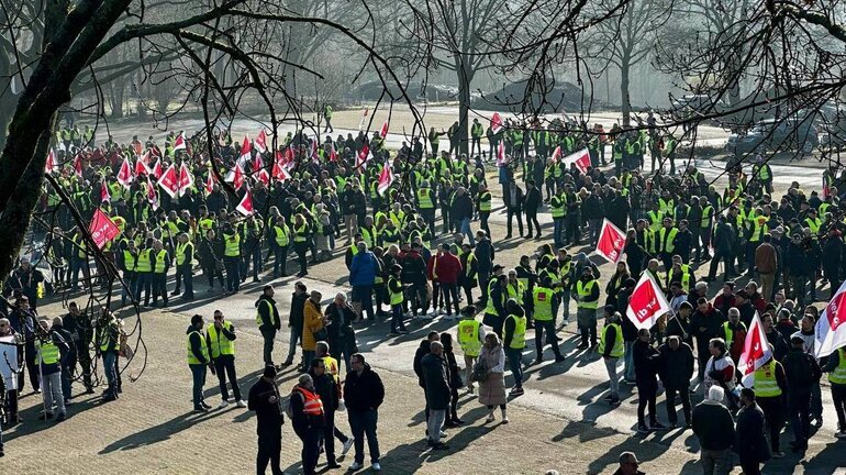 eine große Gruppe von Streikenden hat sich in einem Park versammelt.